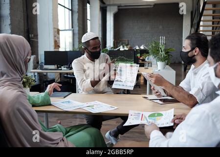 Group of young economists discussing document at working meeting in office Stock Photo