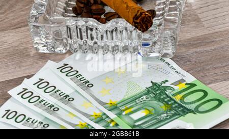 100 euro banknotes with ashtray and cigar on wooden table Stock Photo