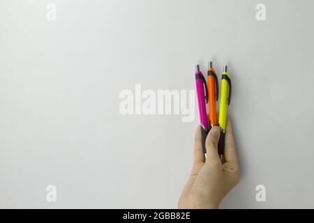 hand of a girl holding three pens of a different color on white background Stock Photo