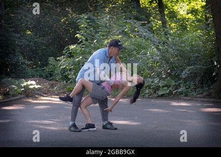 A graceful middle aged Asian American couple dance rigorously on a summer morning  in 2021. In Queens, New York City. Stock Photo