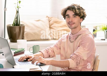 Happy teenager with laptop looking at camera with smile during network Stock Photo