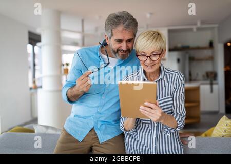 Happy smiling mature couple using digital tablet at home Stock Photo