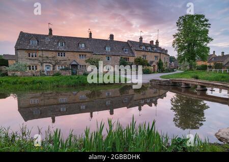 Pretty Cotswolds cottages reflected in the River Eye at dawn in spring in the village of Lower Slaughter, Gloucestershire, England, United Kingdom Stock Photo
