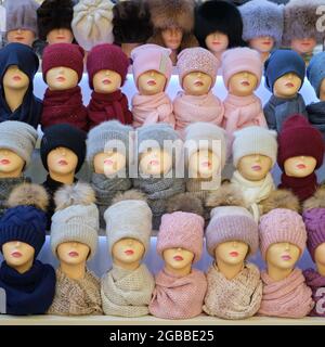 Winter and autumnal warm hats on mannequins in a shop window Stock Photo