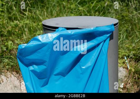 Metal public trash can, blue trash bag Stock Photo
