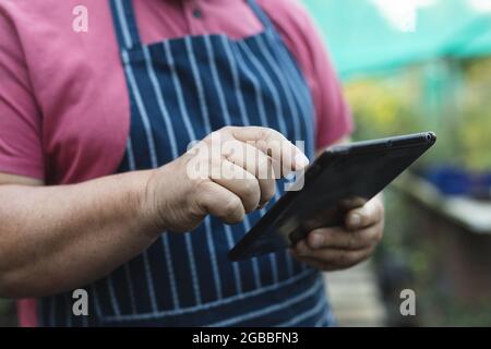 Hands of caucasian male gardener using tablet at garden centre Stock Photo