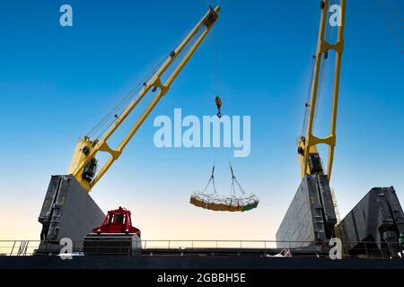 Ship crane lift jumbo sling of sugar bags load into ship hold. Bag cargo loading to ship for export. Stock Photo