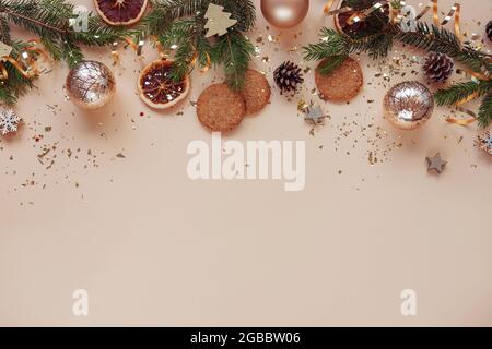 Christmas festive background. Christmas tree branches, balls, cookies and golden confetti on beige background. Top view, flat lay, copy space. Stock Photo