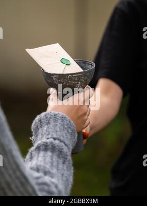 Child handing over a chalice with a brown paper envelope and a green seal Stock Photo