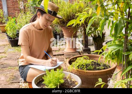 Woman gardener making notes with plant in the front. outdoor Stock Photo