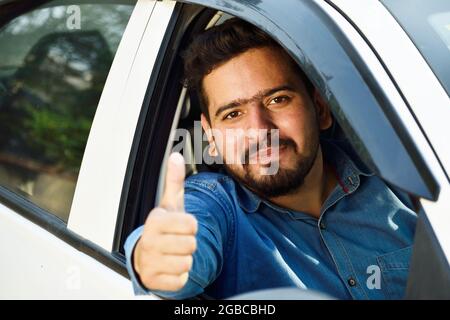 Indian car drive showing thumps up form car's open window Stock Photo