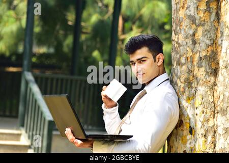 Happy Indian Man Working on Laptop outdoor Stock Photo