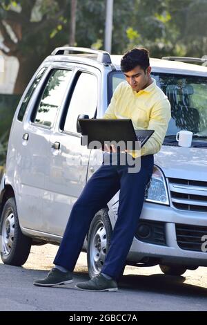Indian man looking on laptop for mechanic on road or vehicle due to puncture car Stock Photo