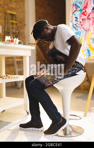 Tired african american male painter at work in art studio Stock Photo
