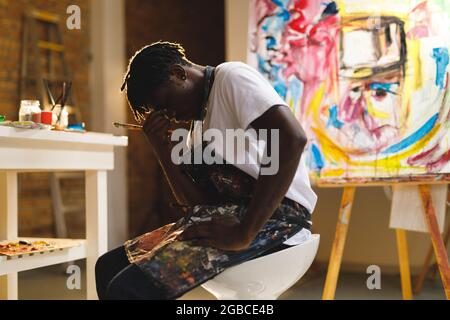 Tired african american male painter at work in art studio Stock Photo