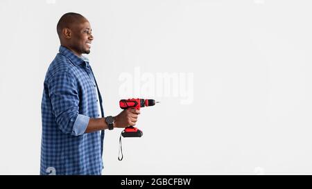 Tool for drilling, fixing and professional builder. African american man holding electric drill over white background Stock Photo
