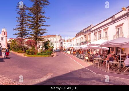 Pavement and streetside cafes and restaurants around the Jardim da Alagoa along Praca Dr. Antonio Padinha Tavira East Algarve Portugal Stock Photo