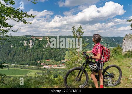 beautiful active senior woman cycling with her electric mountain bike in the rocky Upper Danube Valley on the Swabian Alb between Beuron and Sigmaring Stock Photo