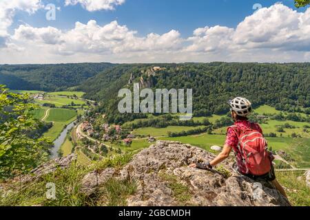 beautiful active senior woman cycling with her electric mountain bike in the rocky Upper Danube Valley on the Swabian Alb between Beuron and Sigmaring Stock Photo