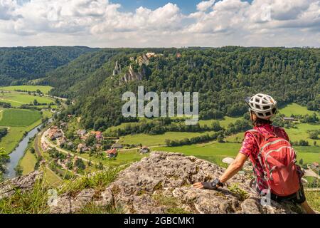 beautiful active senior woman cycling with her electric mountain bike in the rocky Upper Danube Valley on the Swabian Alb between Beuron and Sigmaring Stock Photo