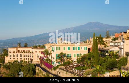 Taormina, Messina, Sicily, Italy. View to Mount Etna from Piazza IX Aprile, early morning, the San Domenico Palace Hotel in foreground. Stock Photo