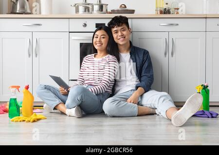 Happy asian man and woman using tablet, looking for house-keeping Stock Photo