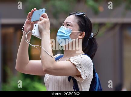 Beijing, China. 03rd Aug, 2021. A female tourist wearing a facemask as a precaution against the spread of covid-19 seen taking selfies at Wangfujing Commercial Street in Beijing. (Photo by Sheldon Cooper/SOPA Images/Sipa USA) Credit: Sipa US/Alamy Live News