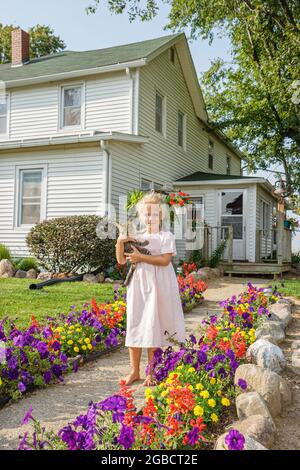 Indiana Shipshewana,Amish Farm Tour,girl child holds holding kitten house home standing front outside, Stock Photo