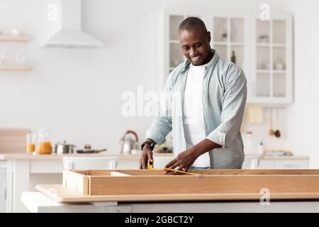 Handyman working at home, repairing, assembling and renovation or new hobby. Man measuring new table with tape-line Stock Photo