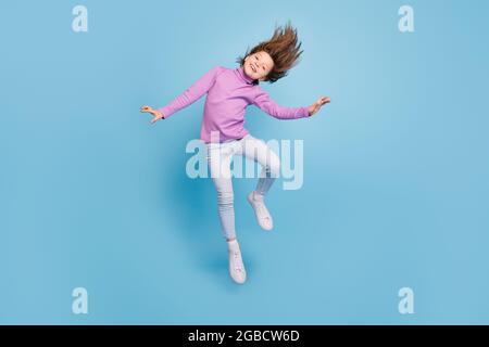 Full length body size photo small girl jumping high throwing hair isolated pastel blue color background Stock Photo