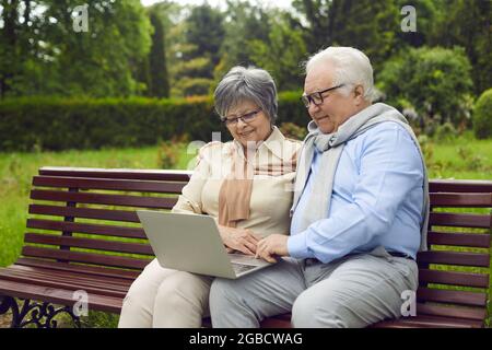 Cheerful senior couple using laptop at park Stock Photo