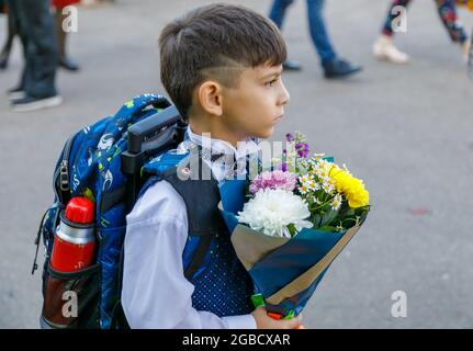 A boy with flowers goes to school for the first time. The first grader goes to study in the first grade. Moscow, Russia, September 2, 2019 Stock Photo