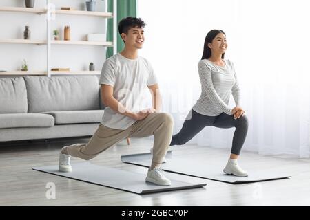 Motivated asian couple exercising at home, copy space Stock Photo