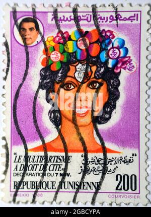 A postage stamp of Tunisia with Image of a smiling lady and former president Bin Ali, plurality of parties is a legal right from the statement of the Stock Photo