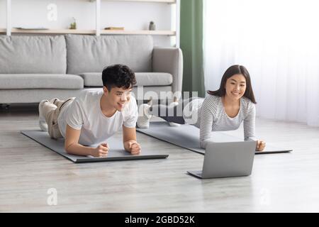 Athletic asian couple having online fitness class Stock Photo