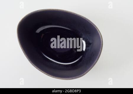 Top view of empty oval shaped dark blue glazed ceramic dish on white background Stock Photo