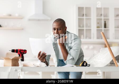 Assembly and renovation at home, homemade during self-isolation. Concentrated african american man reading instruction Stock Photo