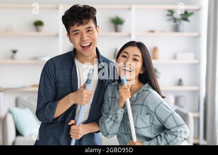 Closeup of positive asian lovers having fun while cleaning apartment Stock Photo