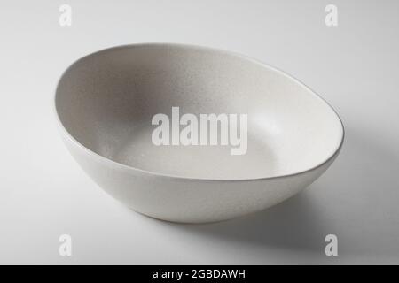 High angle of beige round shaped empty ceramic bowl placed on white table Stock Photo