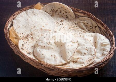 Indian bread roti.Homemade Roti Chapati Flatbread on a rustic wooden board on a white wooden background, side view. Stock Photo