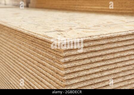 The stack of OSB sheets are stacked in a hardware store on a pallet. plywood with fragments of compressed sawdust, prepared for construction. Selectiv Stock Photo