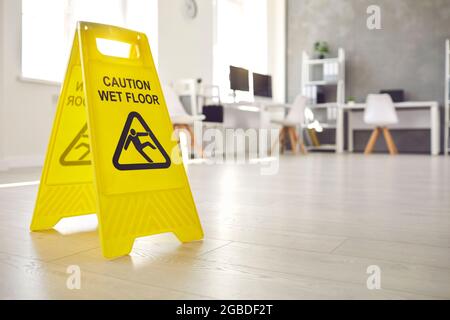 Sign warning about wet floor placed in the office by a commercial cleaning service Stock Photo