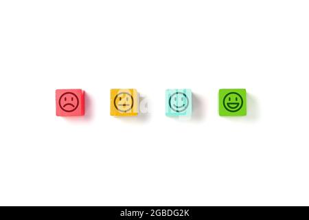 Emoticon faces in colors wooden blocks over white background. Service evaluation and satisfaction survey concepts. Angry, neutral, good mood and happy Stock Photo