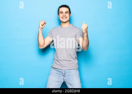 Excited winner man standing with fists up on blue background. Stock Photo