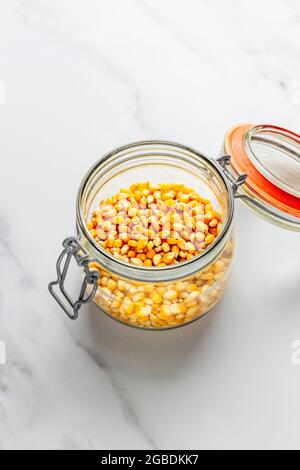 Popcorn in Glass Storage Jar – FOODPIX WHITE - COPYSPACE, ROOM FOR TEXT Stock Photo