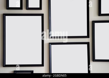 Different size framed photos hanging on the gray wall. Mockup. Stock Photo