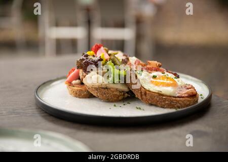 Healthy homemade club sandwich dish with fresh ingredients such as tomato, salad, lettuce, bacon, cauliflower and chicken and a sunny side up egg on a Stock Photo