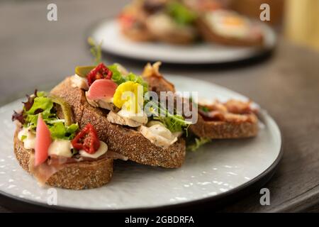 Healthy homemade club sandwich dish with fresh ingredients such as tomato, salad, lettuce, bacon, cauliflower and chicken on a rustic brown bread beau Stock Photo