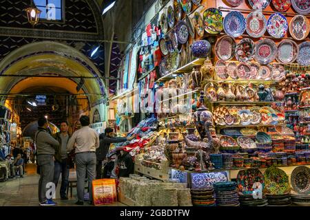 Turkey. 11th Nov, 2017. View of several men, standing, sitting, and arranging wares, next to a corner souvenir shop, displaying a variety of colorful Iznik ceramics in the foreground and textiles at a shop to the rear, with stone-paved floors visible at left, and blue-tiled and painted arch work overhead, in an arched passageway, located in the Grand Bazaar, a large indoor shopping district, constructed by the Ottomans between the 15th and 18th centuries, in the Fatih district of Istanbul, Turkey, November 11, 2017. (Photo by Smith Collection/Gado/Sipa USA) Credit: Sipa USA/Alamy Live News Stock Photo