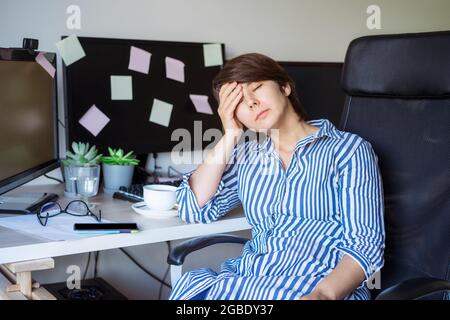 Feeling tired. Frustrated businesswoman taking a break during online work on pc. Suffering from headache, exhausted worker sitting with eyes closed Stock Photo